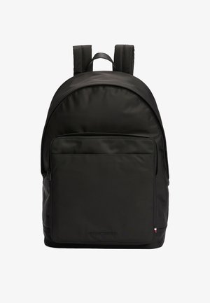 Black nylon backpack with rounded top, padded straps, front zip pocket, and embossed logo at the bottom. Smooth texture with minimalist design.