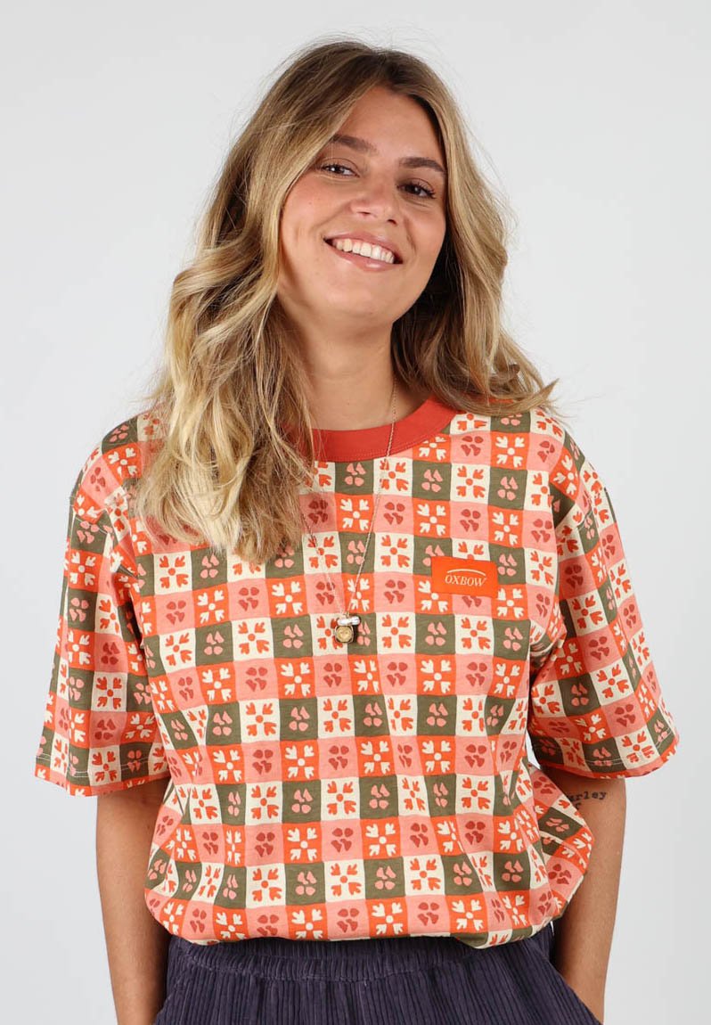 T-shirt à manches courtes, à motifs, en orange, rouge et vert avec des motifs floraux, doté d'un col rond et du logo OX BOW sur la poitrine.