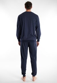 Navy lounge set featuring patterned long-sleeve top and matching joggers with elastic cuffs, made from soft, lightweight fabric.