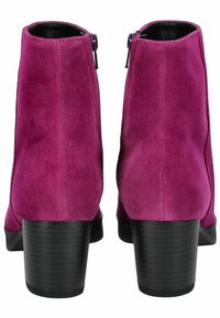 Botas de tobillo de ante magenta con un tacón bloque negro de altura media, que cuentan con una cremallera lateral y un interior de cuero suave.