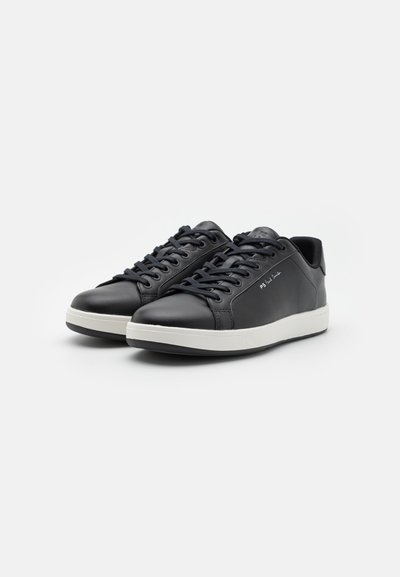 Black leather sneakers with a smooth texture, white rubber sole, rounded toe, and flat laces. Features subtle branding on the side.