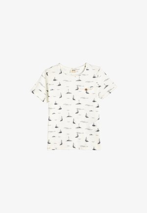 T-shirt bianco in cotone con stampa di un veliero e un faro blu navy. Maniche corte, collo rotondo e un piccolo bottone decorativo sulla tasca del petto.