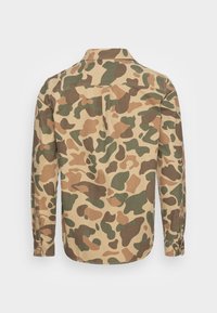 Camicia a maniche lunghe con motivo camouflage in tonalità khaki, verde e marrone, dotata di colletto con bottoni e cucitura singola sul retro.