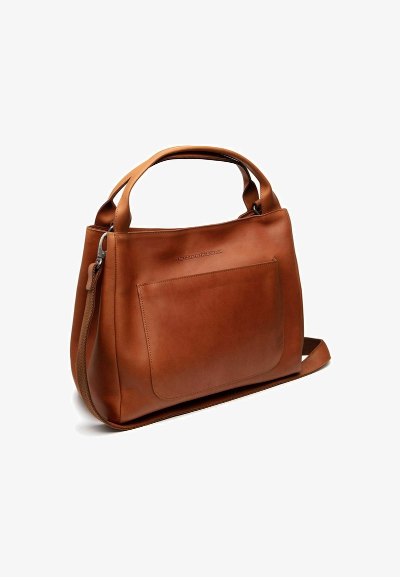Braune Lederhandtasche mit frontseitiger Tasche, oberen Griffen und verstellbarem Schultergurt, steht aufrecht vor einem weißen Hintergrund.