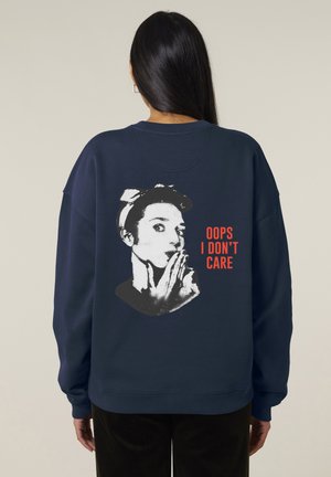 Felpa navy con una vestibilità rilassata, caratterizzata da una grafica in bianco e nero di una persona che si tiene il dito sulle labbra e il testo "OOPS I DON'T CARE" in rosso.