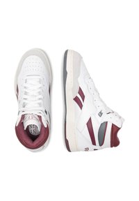 Biele a bordové vysoké tenisky so perforovanou špičkou, textúrovaným jazykom a šedými akcentmi; vyrobené z kože a sieťoviny.