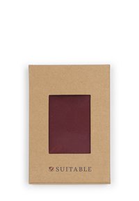 Bruine kartonnen doos met een transparant venster dat een bordeauxrode stof toont. Het merk "Suitable" is onderaan afgedrukt.