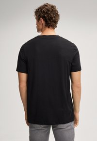 Zwarte t-shirt met korte mouwen, gemaakt van zachte katoen, met een ronde halslijn en een relaxed fit, vanuit de rug getoond met zichtbare naden.