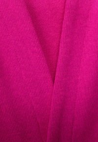 Tessuto lavorato a maglia fucsia con una texture a coste, caratterizzato da un scollo a V e sezioni sovrapposte, creando un aspetto stratificato.