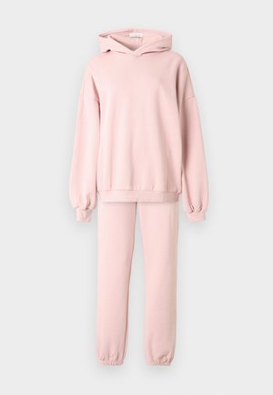Σετ ροζ φούτερ με κουκούλα και αντίστοιχο παντελόνι φόρμας. Το φούτερ έχει κουκούλα με κορδόνι, μακριά μανίκια και ριμπ μανσέτες. Το παντελόνι διαθέτει ελαστική μέση και ριμπ μπατζάκια.