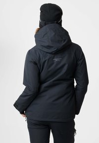 Black insulated jacket with a hood, made of smooth fabric. Features logo on the back, adjustable cuffs, and zippers on pockets.