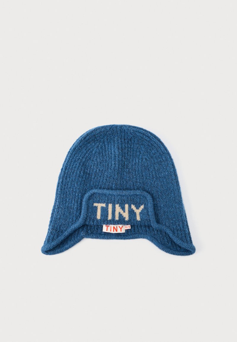 Blauer Strick-Mütze mit gerippter Textur, featuring ein beiges "TINY"-Logo auf der Vorderseite und einem kleinen roten Etikett an der Seite.