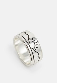 Anel prateado com uma banda texturizada, apresentando um design de sol e montanha gravado em preto na superfície. Acabamento interior suave.