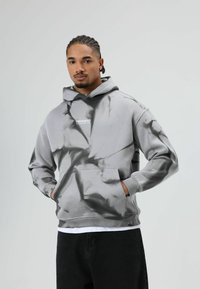 Grijze hoodie met een zwart marmerpatroon, voorzien van een kangoeroezak en een capuchon met trekkoord, met de tekst "PRESENTED" op de borst.