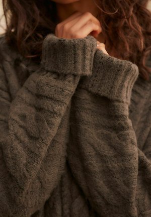 Kuscheliger brauner Strickpullover mit gerippten Bündchen und kunstvollen Texturmuster. Der Stoff wirkt weich und warm, ideal für kaltes Wetter.