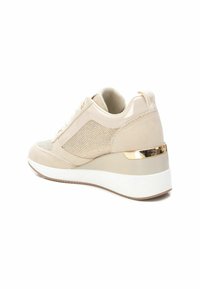 Zapatillas deportivas en cuña color beige con parte superior de malla texturizada, detalles de ante y una franja dorada en el talón. Presenta una suela blanca y beige.
