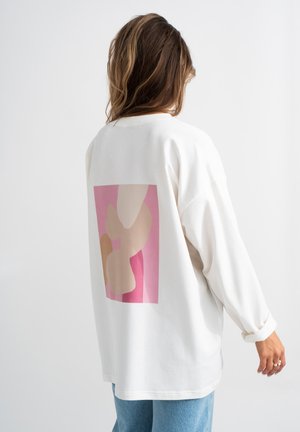 Wit sweatshirt met lange mouwen en een kleurrijk abstract ontwerp in tinten roze en beige op de achterkant, met een relaxed pasvorm en een zachte textuur.