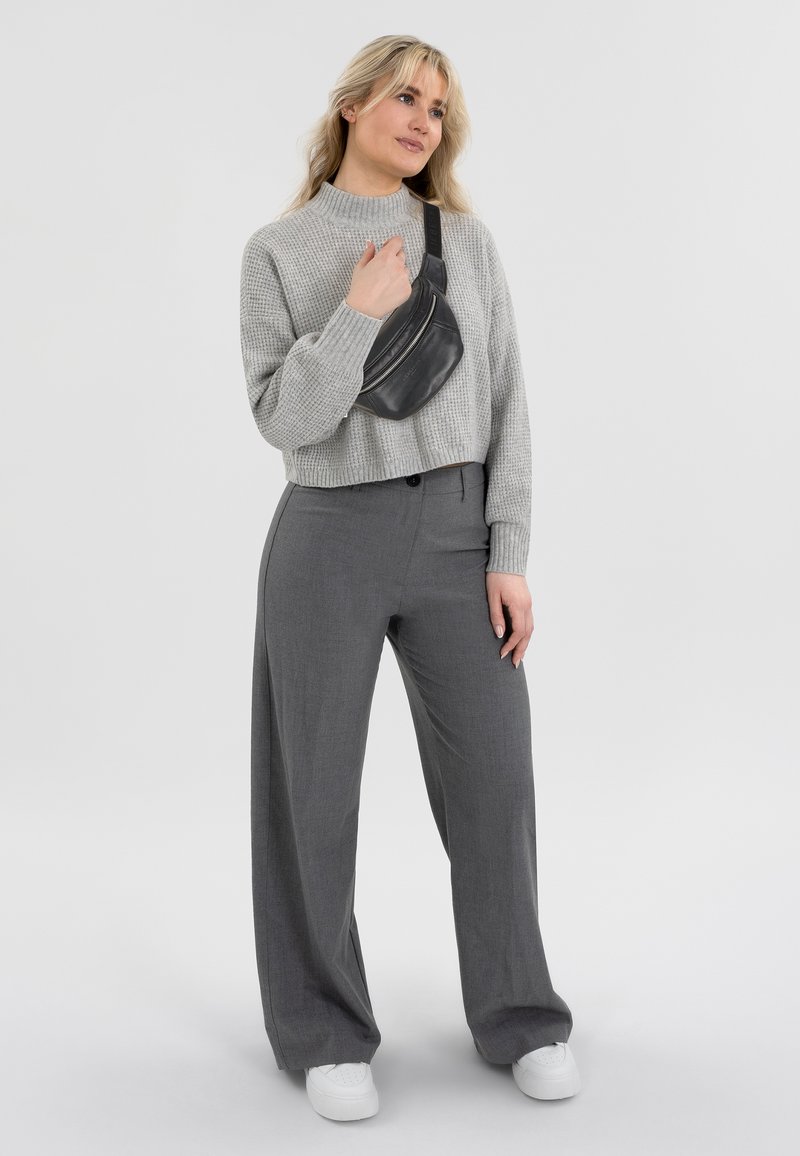 Grau geschnittenes Sweater mit strukturiertem Muster, kombiniert mit hoch taillierten grauen weitem Hosen und einer kleinen schwarzen Umhängetasche. Weiße Schuhe.