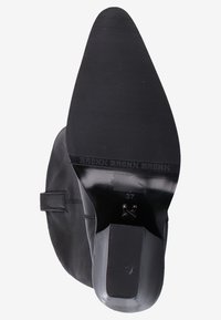 Botín de cuero negro hasta el tobillo con puntera puntiaguda, textura suave, tacón bajo y detalle de hebilla lateral. Talla 37 marcada en la suela.