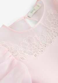 Abito rosa chiaro con maniche a sbuffo trasparenti e un design ricamato a fiori lungo il corpetto. Il tessuto appare liscio e delicato.
