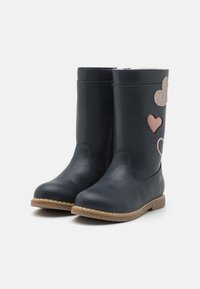 Bottes en cuir bleu marine avec un bout rond, semelle texturée couleur tan, et appliqués décoratifs en forme de cœur et de nuage en matériaux roses et scintillants.