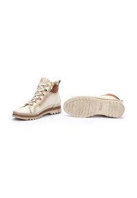 High-top boots made of beige leather with brown accents, featuring a side zipper, rubber sole with a textured pattern, and reinforced toe.