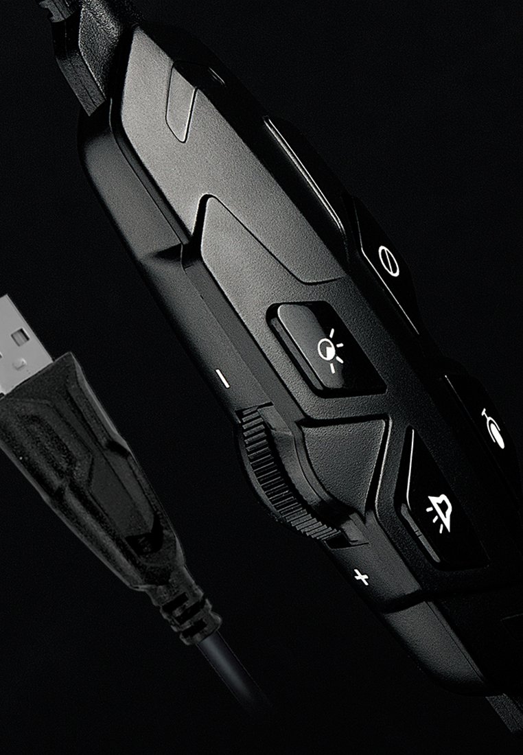 Schwarzes, kabelgebundenes Gaming-Headset mit texturiertem Griff, verstellbarem Lautstärkeregler und mehreren Tasten auf einer matten Oberfläche; USB-Anschluss sichtbar.