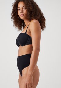 Black underwire bra with molded cups, adjustable thin straps, and high-waisted black bikini bottoms. Smooth fabric, minimal detailing.