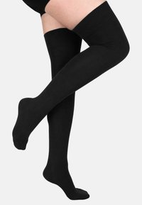 Schwarze Über-die-Knie-Stulpen aus einem weichen, glatten Stoff mit einem gerippten oberen Bund für optimalen Halt. Sie verfügen über ein nahtloses, verlängertes Design für einen enganliegenden Look.