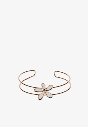 Złota otwarta bransoletka mankietowa z białym emaliowanym kwiatem o pięciu płatkach, umieszczonym na podwójnym drucianym pasku na białym tle.