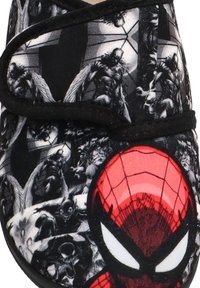 Máscara roja de Spider-Man con patrón de telaraña sobre un fondo en blanco y negro que presenta personajes de cómic alados y musculosos.