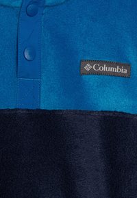 Fleece-Pullover in Blau und Marineblau. Mit Druckknöpfen, einem gewebten Logo und einer strukturierten Oberfläche. Entworfen für Wärme und Komfort.