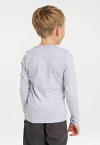 Long-sleeve grey t-shirt in soft, heathered fabric with a crew neckline, featuring a relaxed fit and straight hem, paired with dark pants.