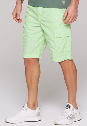 Light green cargo shorts with a textured fabric, featuring side pockets and elastic hems, paired with white athletic shoes.