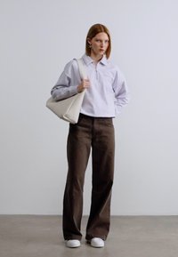 Φούτερ με φερμουάρ ανοιχτόχρωμο μοβ, παντελόνι καφέ σκούρο με φαρδιά πόδια, λευκά αθλητικά παπούτσια και κρεμ τσάντα ώμου. Ομαλό ύφασμα και άνετη εφαρμογή.