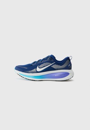 Niebieski but do biegania Nike z białym logo Swoosh, paskowanym wzorem i grubą białą podeszwą z detalami w jasnoniebieskim i fioletowym gradiencie.