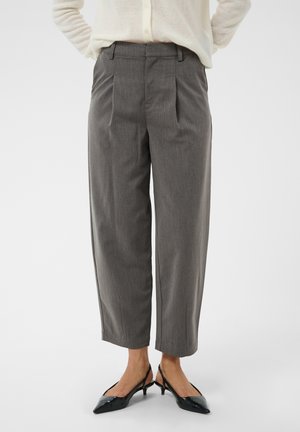 Pantalons gris sur mesure de longueur moyenne portés avec des talons slingback noirs pointus et un pull crème, montrés de la taille aux pieds.