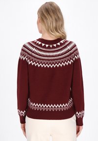Burgundy színű pulóver fehér kötött mintákkal a nyakrészen és az alján, kerek nyakkivágással, valamint bordás mandzsettákkal és aljjal.