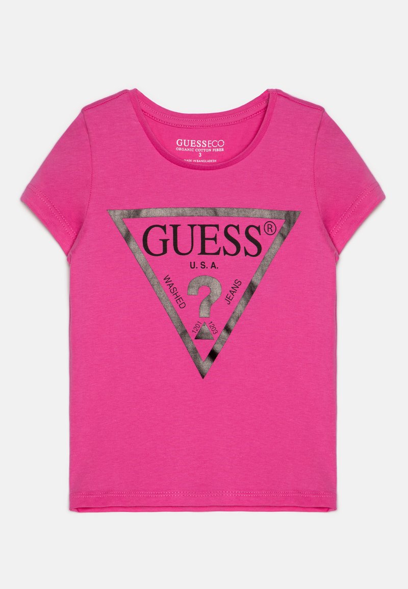 Roosa puuvillane T-särk lühikeste varrukatega ja ümar kaelus. Kaunistatud musta kolmnurkse logoga, millel on "GUESS" ja tekst metallikhõbedasena.