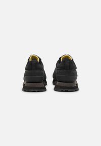 Scarpe sportive nere con tomaia in suede e rete, colletto imbottito alla caviglia e suola scura texture con accenti chiari.