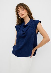Top blu navy con scollatura drappeggiata e maniche corte, caratterizzato da un motivo a zebra testurizzato in un tessuto morbido. Design a vestibilità ampia.