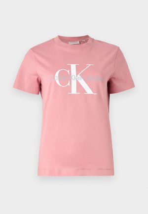Pink cotton t-shirt with short sleeves. Features a large white "CK" logo and "Calvin Klein Jeans" text printed in light blue underneath.