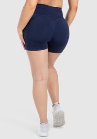 Middengouden compressie-shorts met een hoge taille, een gladde textuur en gebogen naaddetails op de rug voor een contoured uiterlijk.