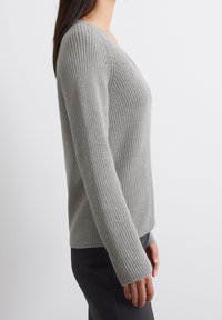 Maglione lavorato a maglia grigio chiaro con scollo a V, texture a coste e maniche lunghe. Forma aderente, che arriva ai fianchi, con orlo dritto.
