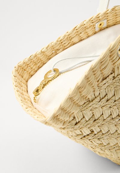 Sac à main en paille tissée de couleur beige naturel, doté d'une fermeture éclair dorée et d'un tissu intérieur blanc. Accentué par une couture claire et des quincailleries.