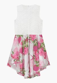 Robe sans manches blanche avec un motif floral rose et vert sur la jupe en tulle. Corsage texturé avec un design à œillets, fermeture éclair au dos.
