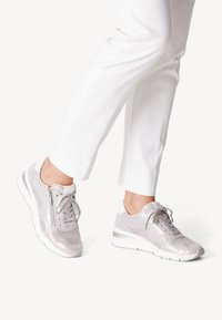 Light gray athletic shoes with a mix of smooth and textured materials, featuring a lace-up front, side zipper, and a contrasting sole.