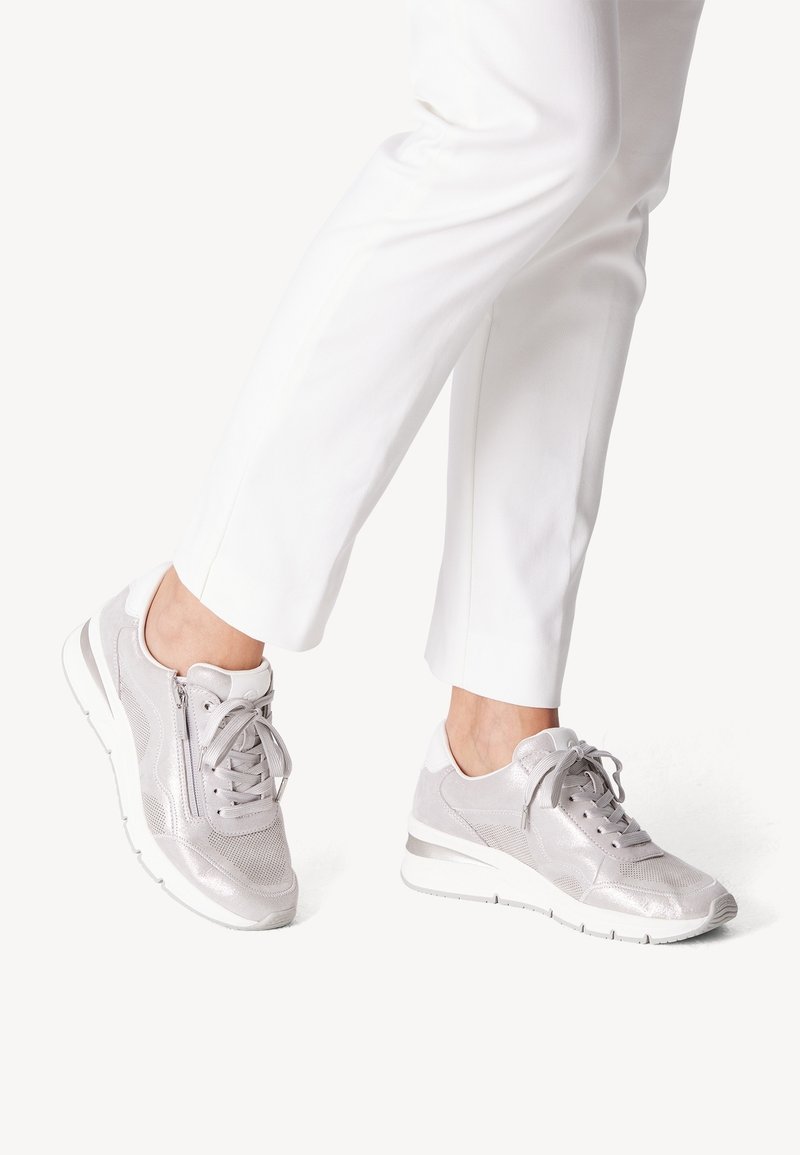 Light gray athletic shoes with a mix of smooth and textured materials, featuring a lace-up front, side zipper, and a contrasting sole.