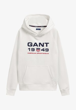 Bílá mikina s kapucí, na níž se nachází velká tmavě modrá výšivka "GANT 1949" a "AMERICAN SPORTSWEAR." Obsahuje přední kapsu.