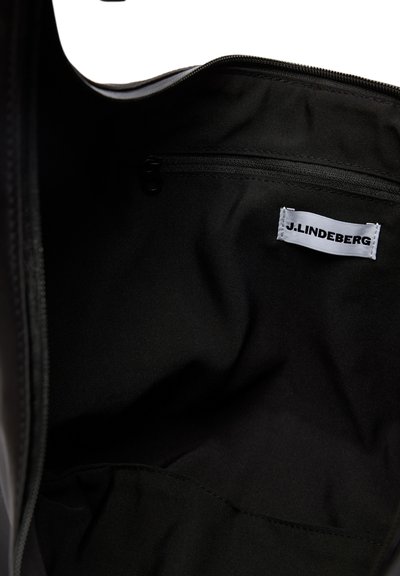 Wnętrze czarnej materiałowej torby z kieszenią na zamek i białą metką z nazwą marki J.LINDEBERG.